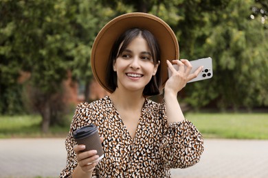 Photo of Beautiful woman with smartphone listening to voice message outdoors