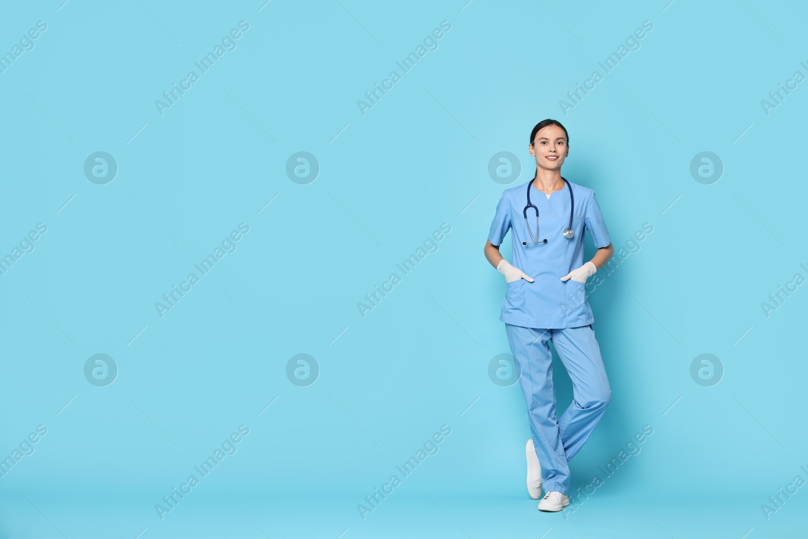 Photo of Smiling nurse in uniform on light blue background. Space for text