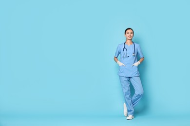 Photo of Smiling nurse in uniform on light blue background. Space for text