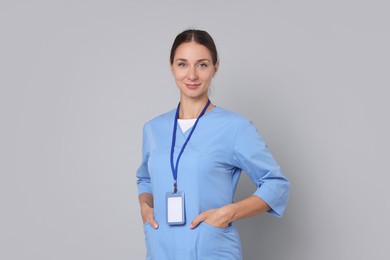 Nurse in medical uniform with badge on grey background