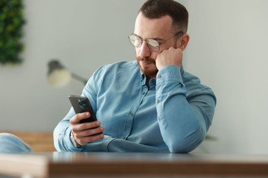 Photo of Handsome man looking at smartphone in office