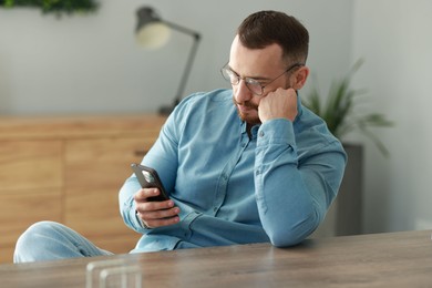 Photo of Handsome man looking at smartphone in office