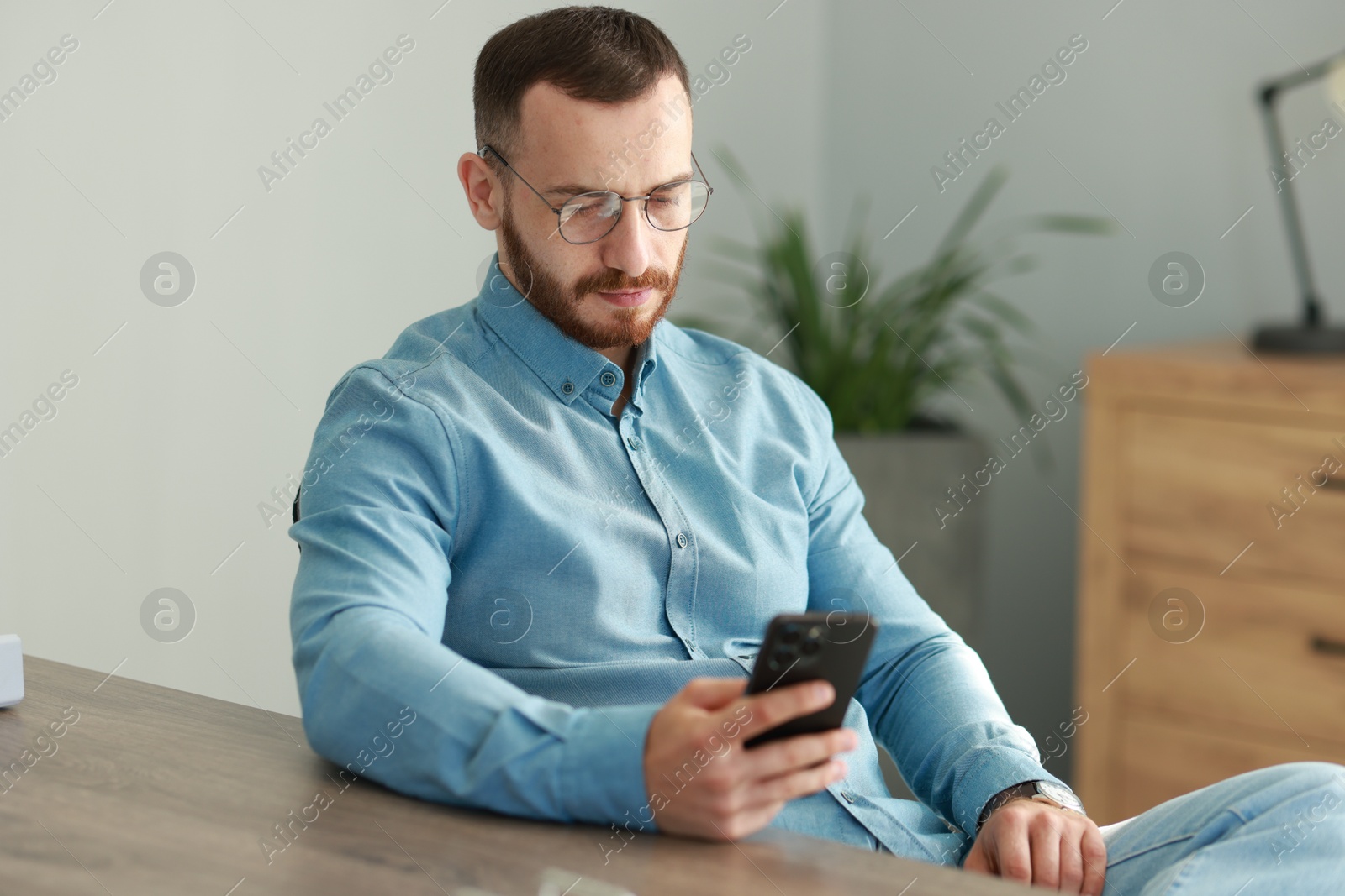 Photo of Handsome man looking at smartphone in office