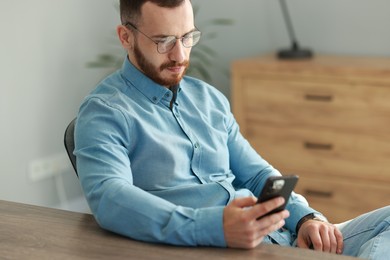 Handsome man looking at smartphone in office