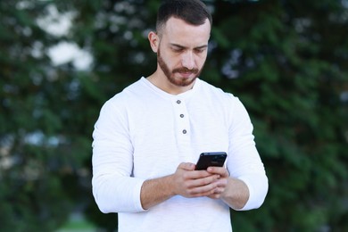 Photo of Handsome man using smartphone on blurred background