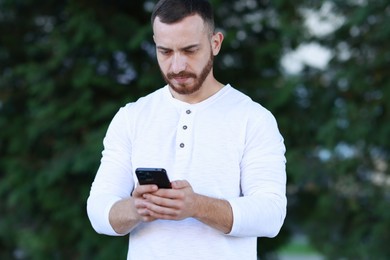 Photo of Handsome man using smartphone on blurred background