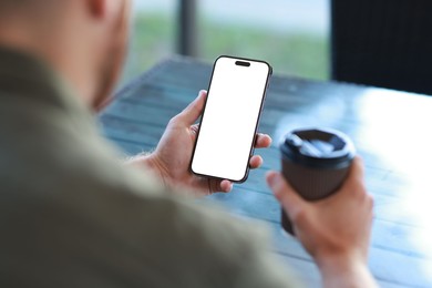 Photo of Man with paper cup using smartphone at outdoor cafe, closeup. Space for design