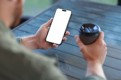 Photo of Man with paper cup using smartphone at outdoor cafe, closeup. Space for design