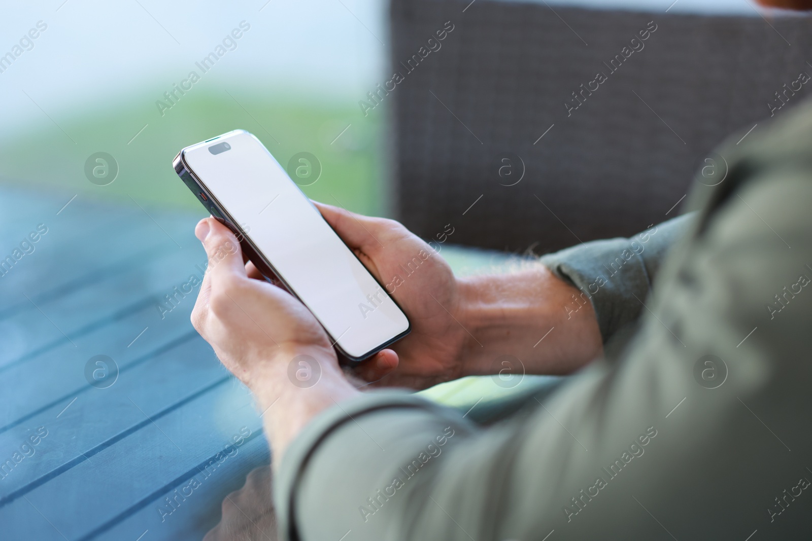 Photo of Man with paper cup using smartphone at outdoor cafe, closeup. Space for design