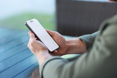 Photo of Man with paper cup using smartphone at outdoor cafe, closeup. Space for design