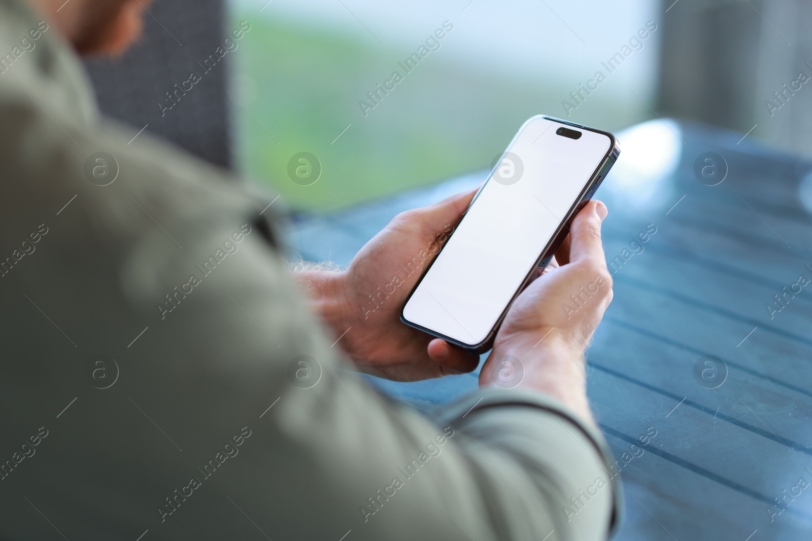 Photo of Man with paper cup using smartphone at outdoor cafe, closeup. Space for design