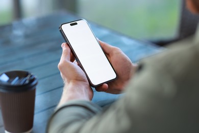 Man with paper cup using smartphone at outdoor cafe, closeup. Space for design