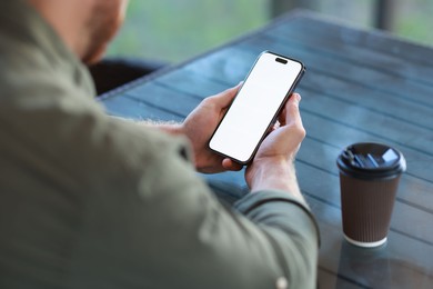 Photo of Man with paper cup using smartphone at outdoor cafe, closeup. Space for design