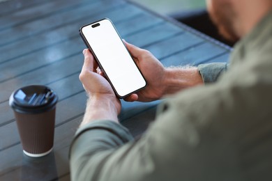 Photo of Man with paper cup using smartphone at outdoor cafe, closeup. Space for design