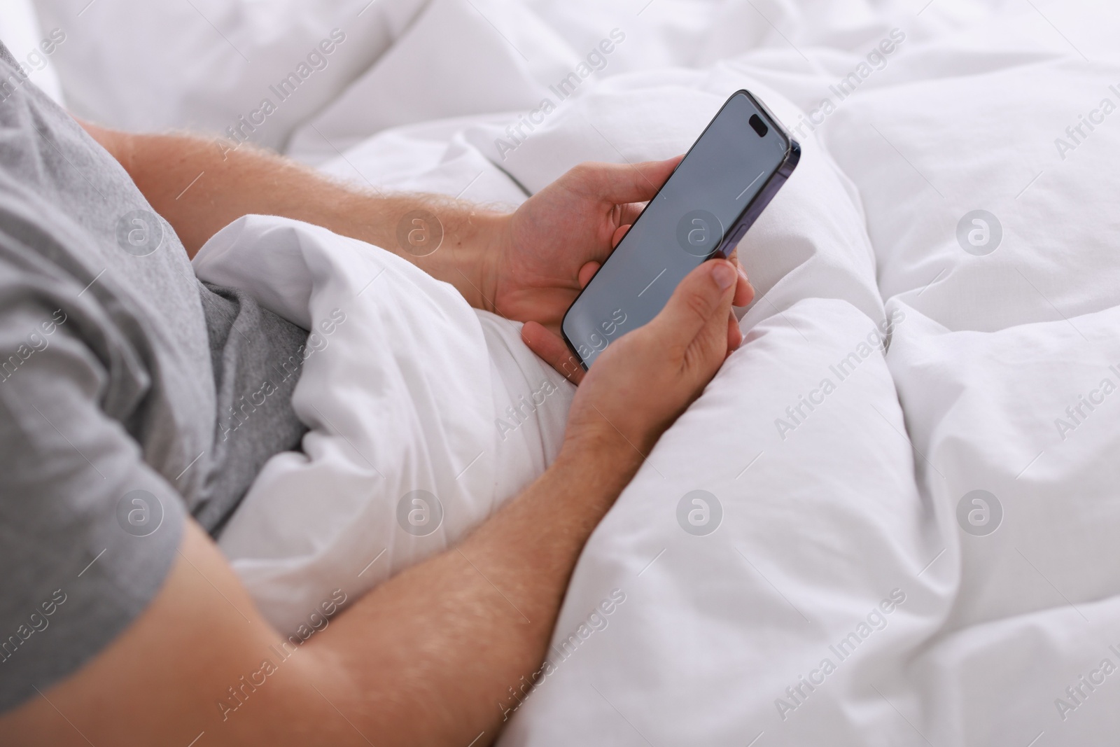 Photo of Man using smartphone in bed, closeup view