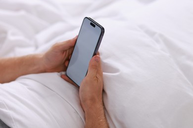 Photo of Man using smartphone in bed, closeup view