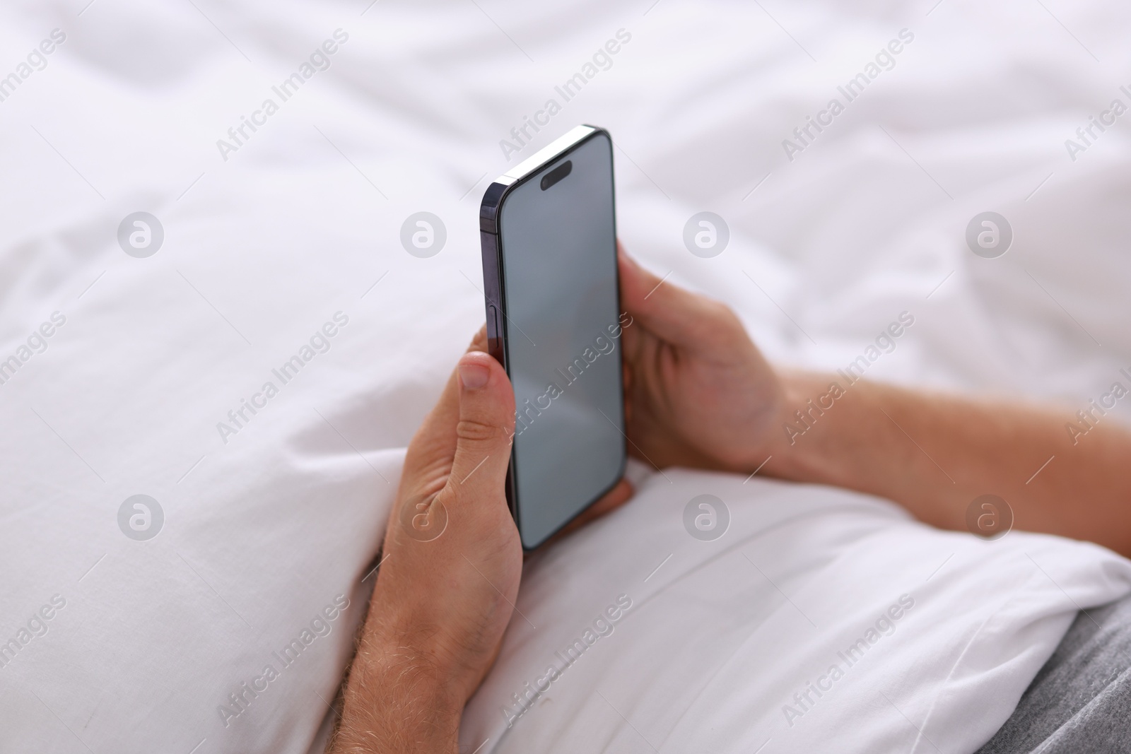 Photo of Man using smartphone in bed, closeup view