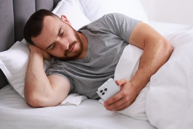 Photo of Handsome man using mobile phone in bed