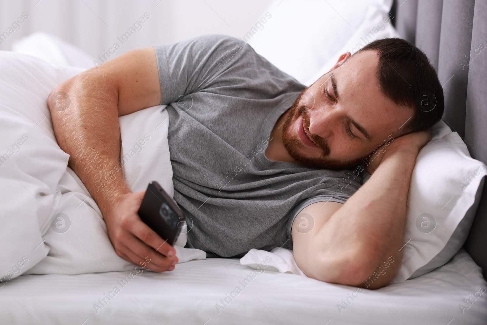 Photo of Handsome man using mobile phone in bed