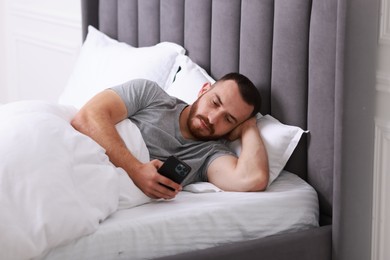 Photo of Handsome man using mobile phone in bed