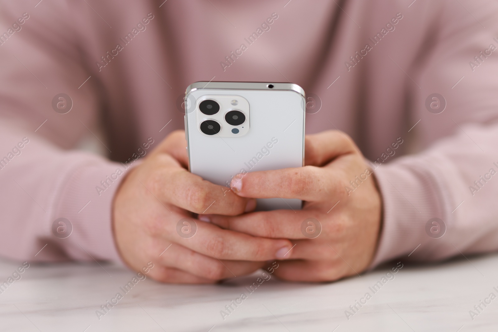 Photo of Man using smartphone at white table indoors, closeup