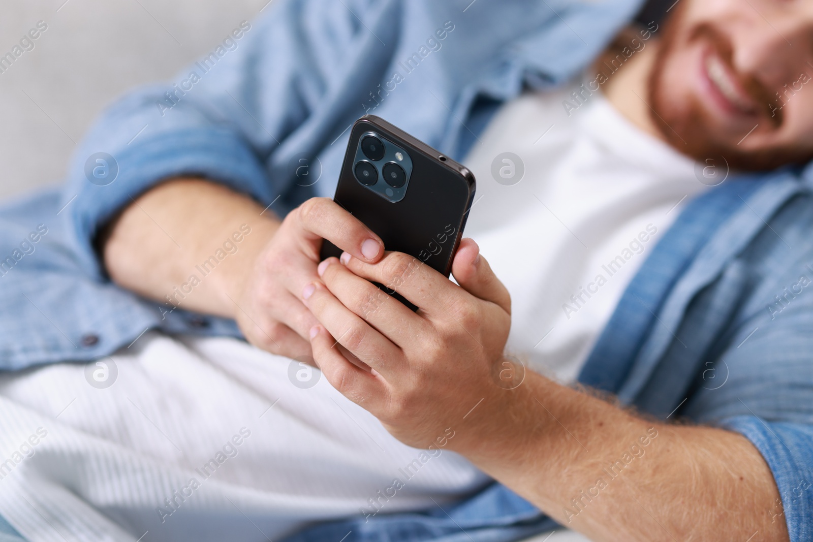 Photo of Man using modern smartphone indoors, closeup view