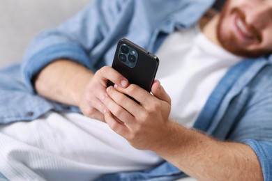 Man using modern smartphone indoors, closeup view