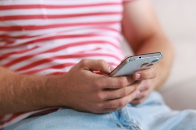 Man using smartphone on blurred background, closeup