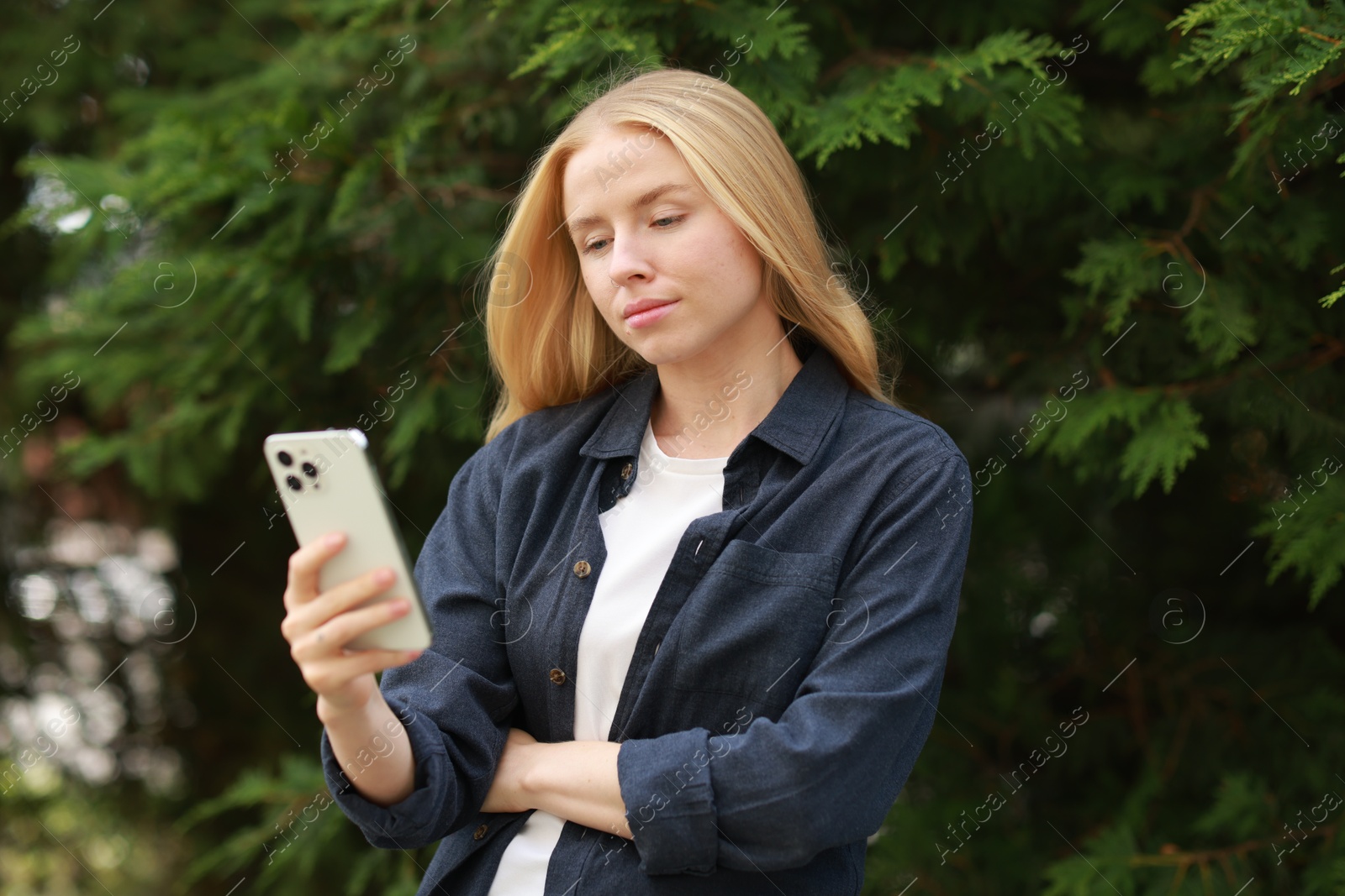 Photo of Beautiful woman using smartphone near tree outdoors