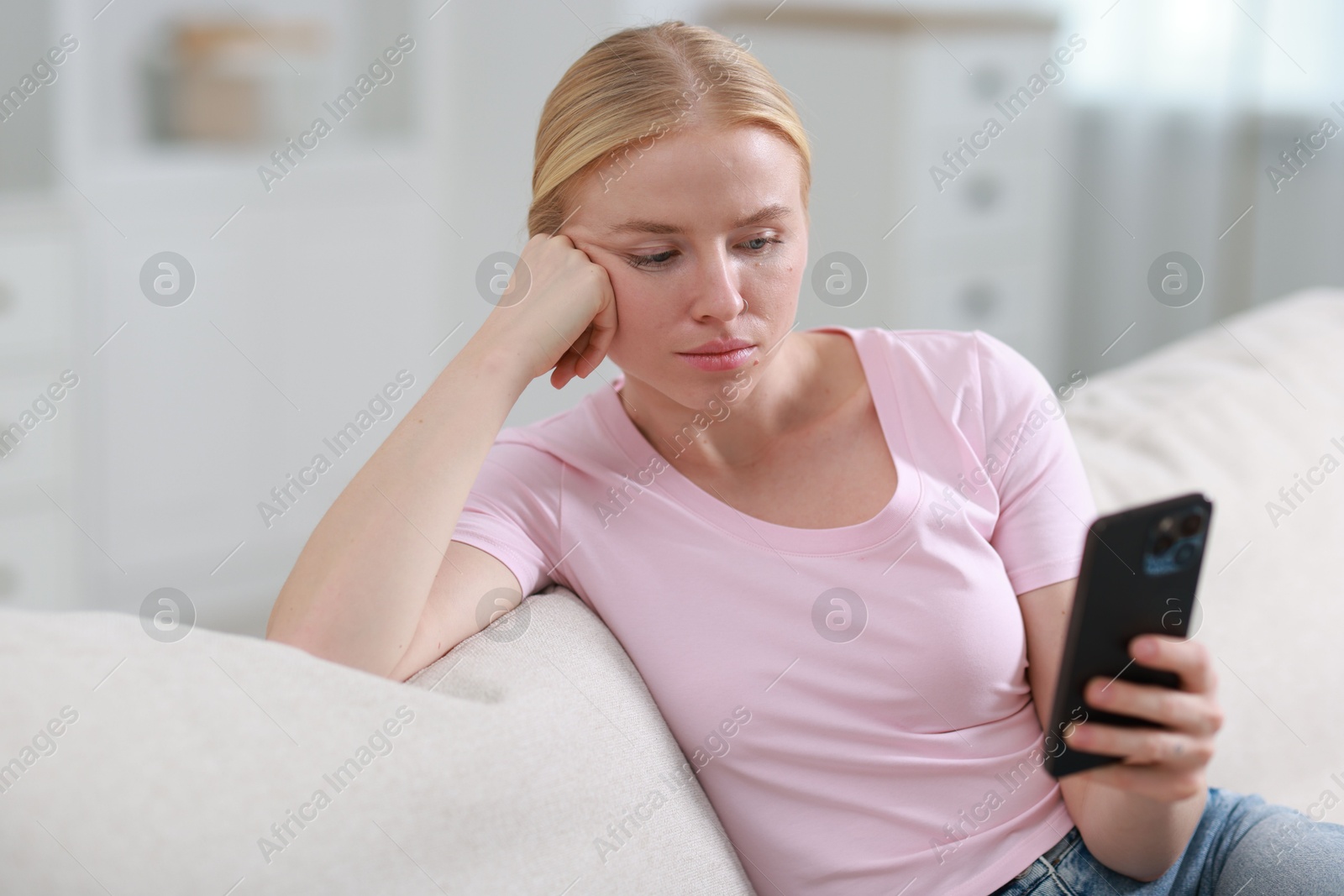 Photo of Beautiful woman using smartphone on sofa indoors