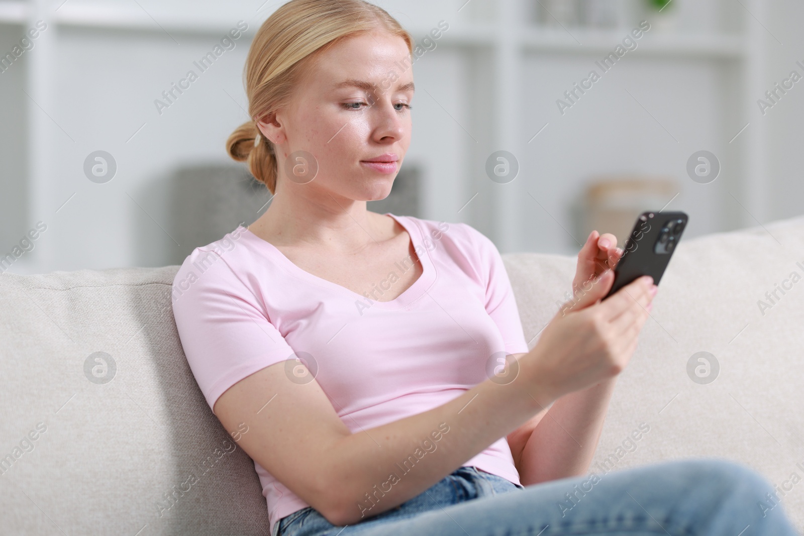 Photo of Beautiful woman using smartphone on sofa indoors