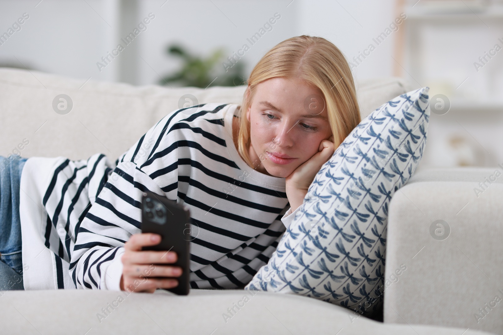 Photo of Beautiful woman using smartphone on sofa indoors