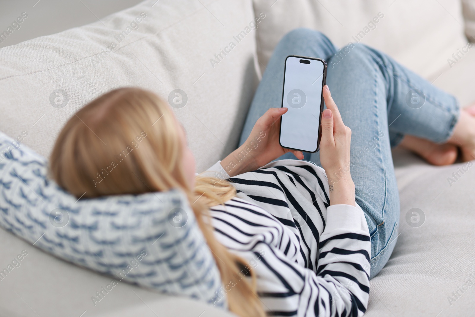 Photo of Woman using smartphone on sofa at home