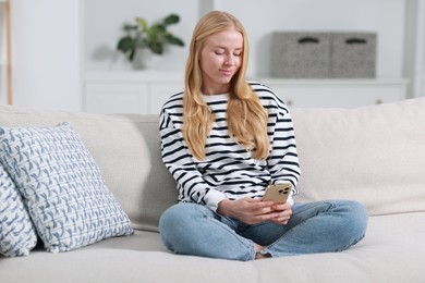 Photo of Beautiful woman using smartphone on sofa indoors