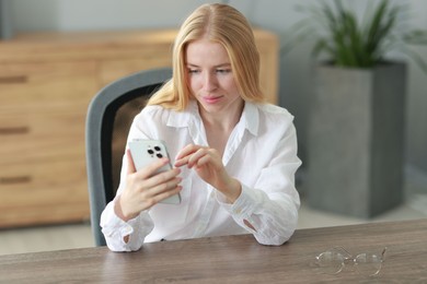 Beautiful woman using smartphone at table in office