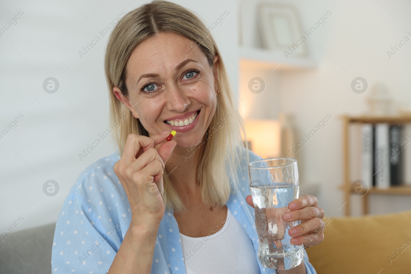 Photo of Menopause, hormone replacement therapy. Happy woman with glass of water and pill at home