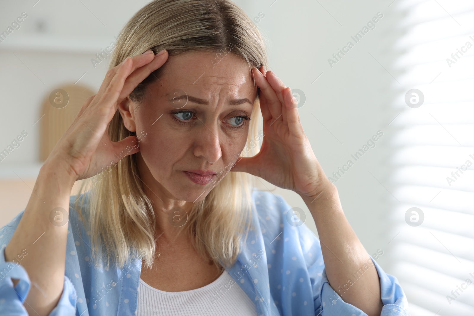 Photo of Menopause. Woman suffering from headache at home