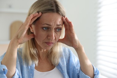 Photo of Menopause. Woman suffering from headache at home