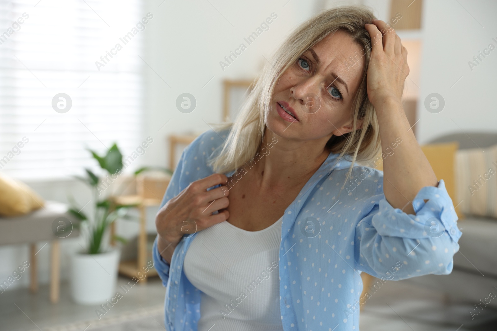 Photo of Menopause. Woman suffering from headache at home, space for text