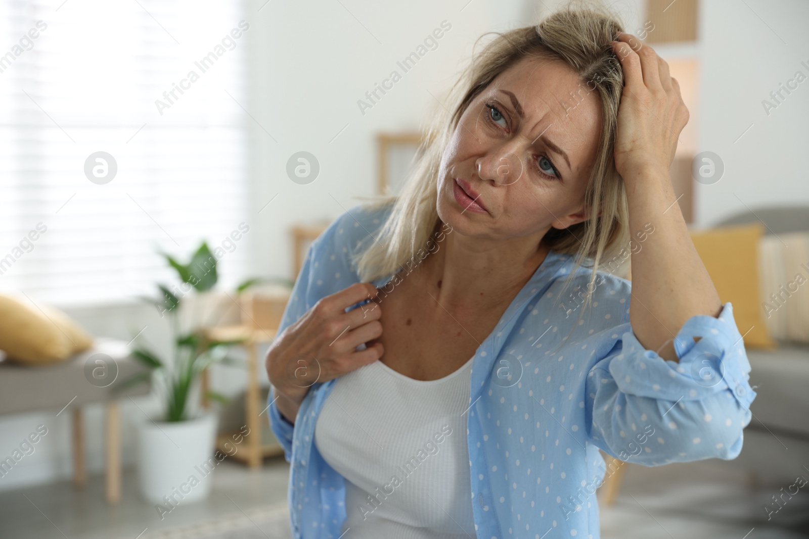 Photo of Menopause. Woman suffering from headache at home, space for text