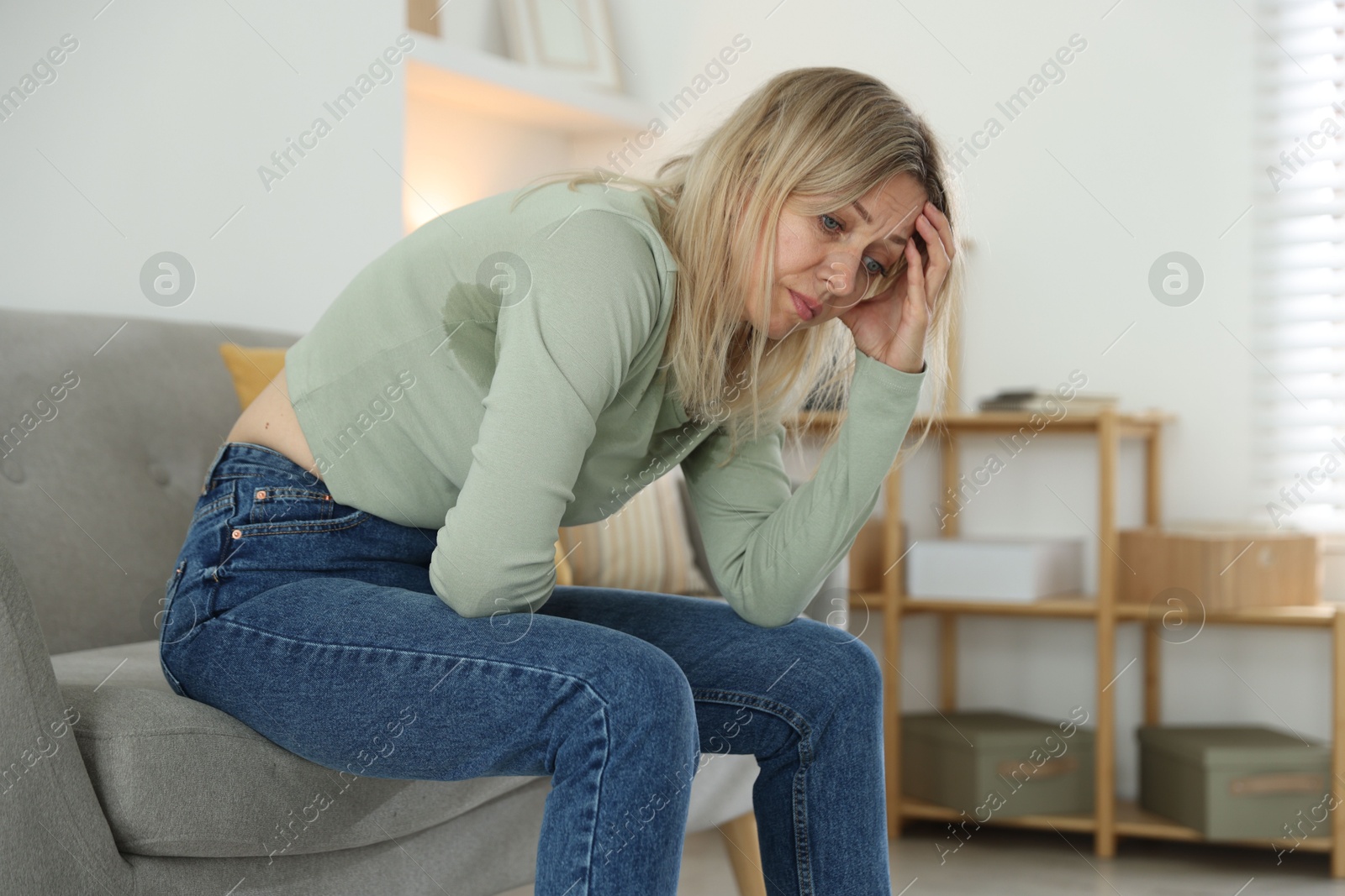 Photo of Menopause. Woman suffering from headache on sofa at home