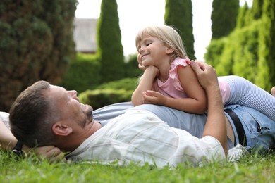 Father and his daughter spending time together on green lawn in park