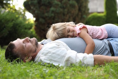 Father and his daughter spending time together on green lawn in park