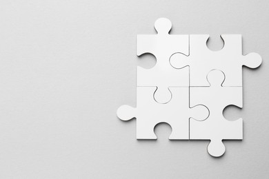 Photo of White puzzle pieces on grey background, top view. Space for text