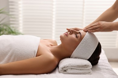 Photo of Attractive woman enjoying face massage in spa salon