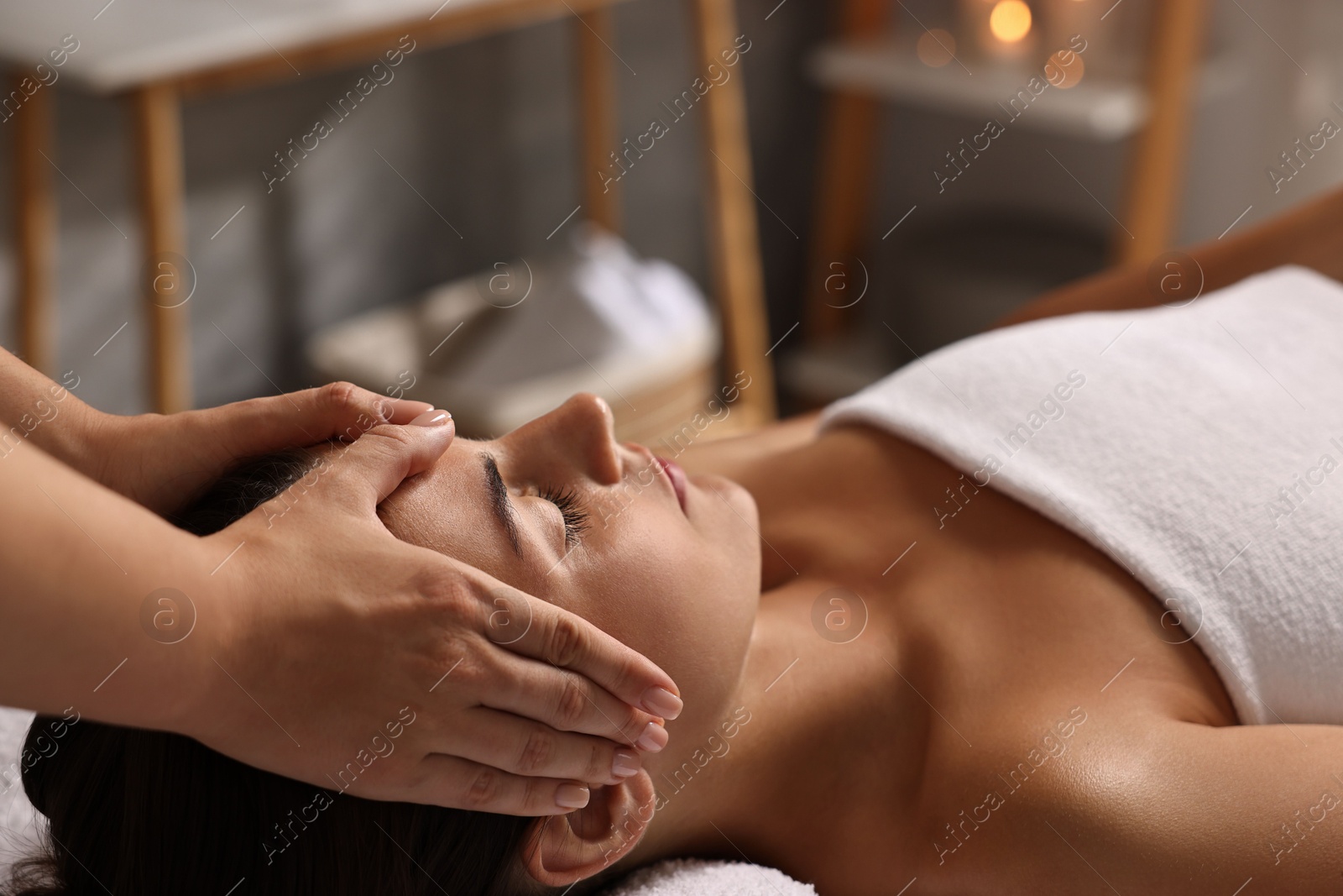 Photo of Attractive woman enjoying face massage in spa salon, closeup