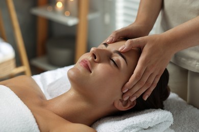 Photo of Attractive woman enjoying face massage in spa salon, closeup