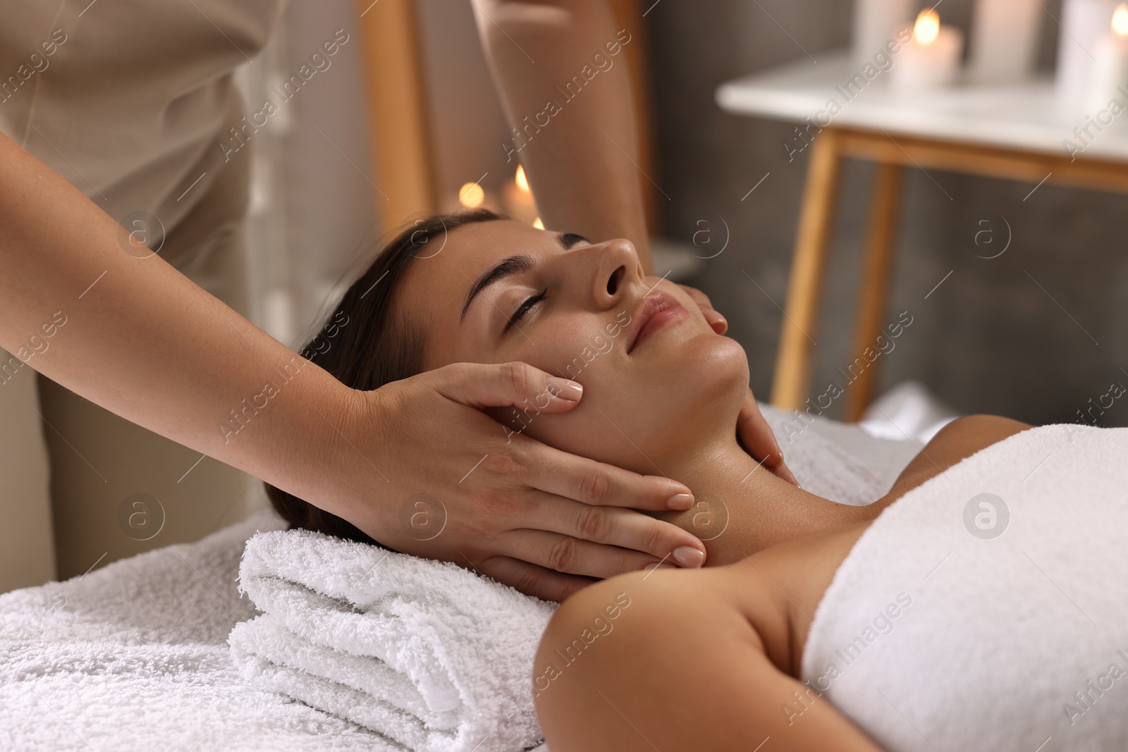 Photo of Attractive woman enjoying face massage in spa salon, closeup