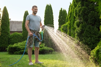 Man watering lawn with hose in backyard