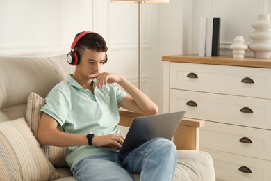 Photo of Portrait of teenage boy with laptop and headphones at home